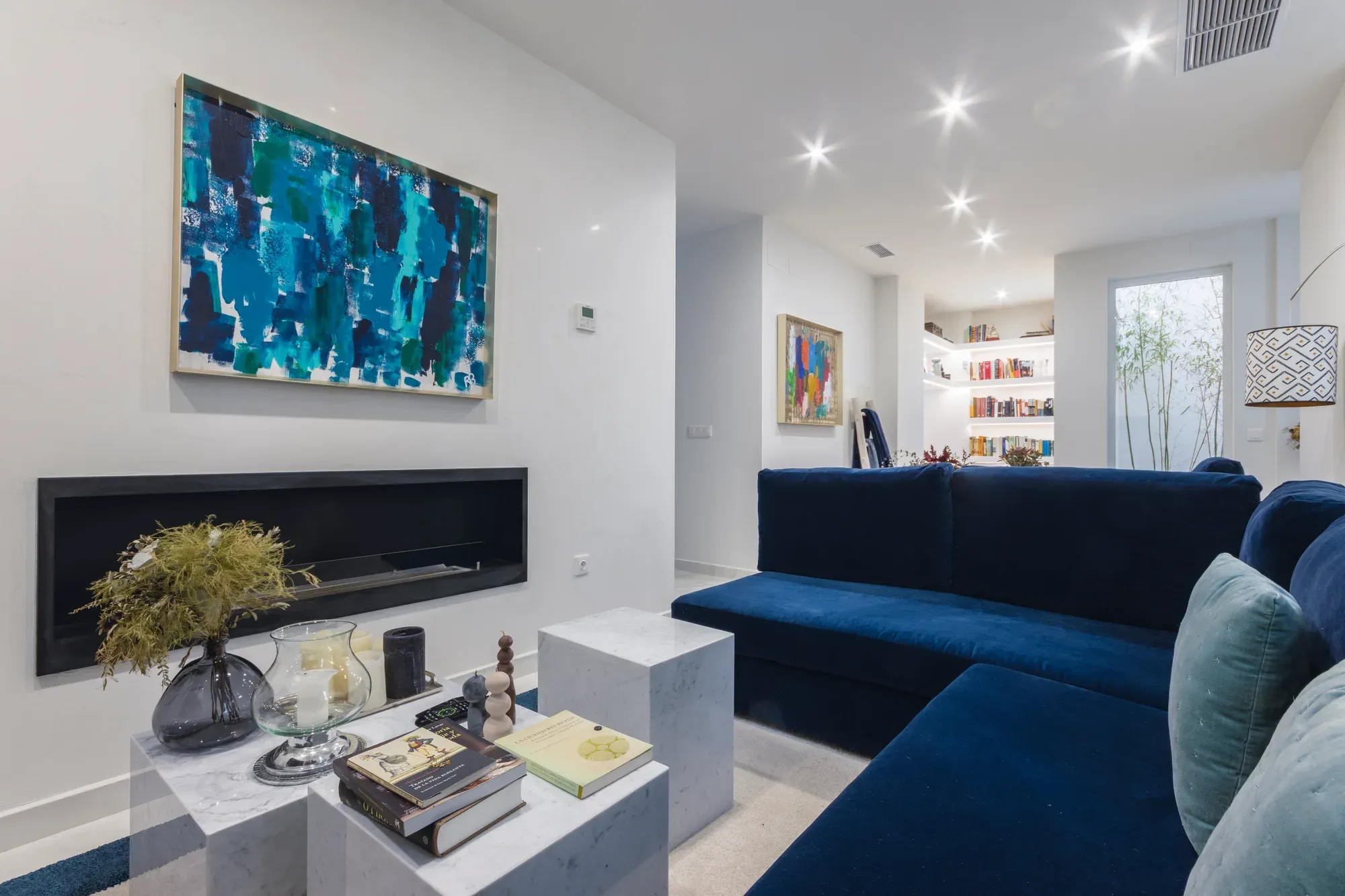 Salón reformado con chimenea lineal empotrada y sofá azul