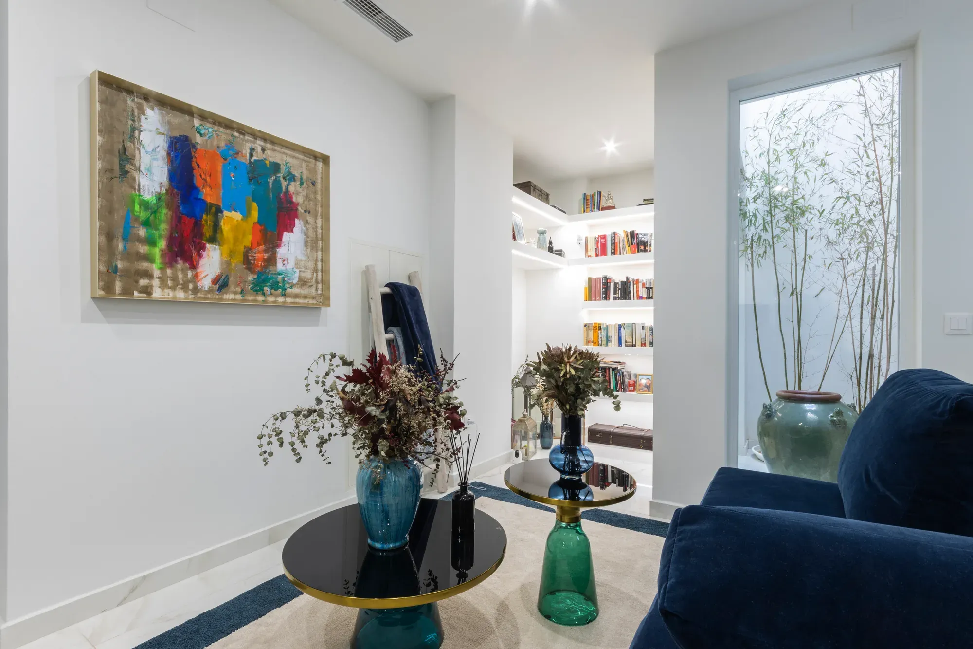 Salón reformado de doble altura con sofá azul y ventanal