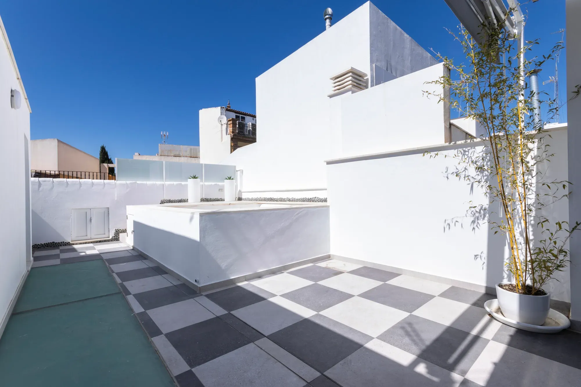 Terraza reformada con solado ajedrezado en dos tonos y jardineras