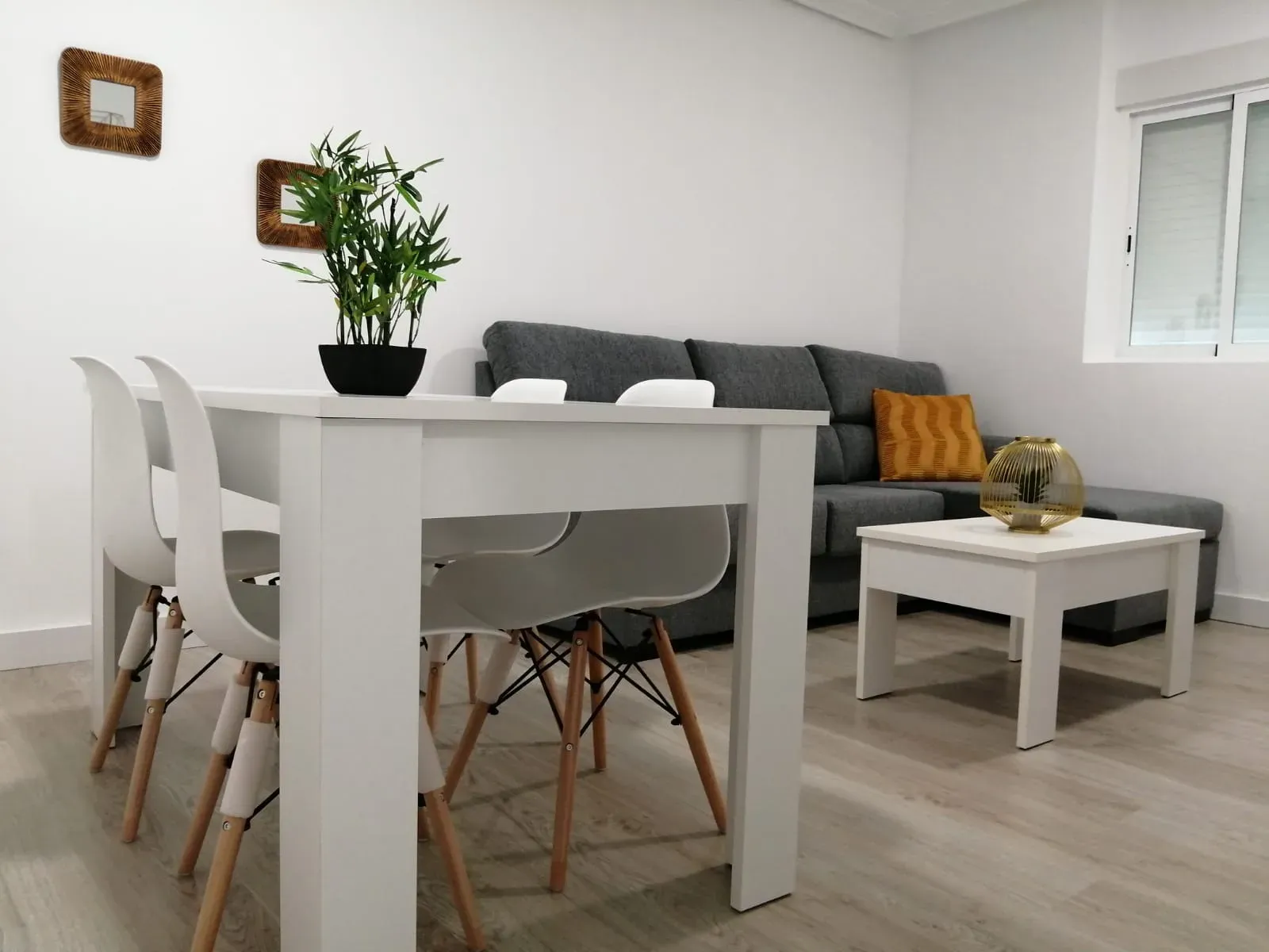 Comedor y salón de un piso pequeño reformado, con suelo de madera clara