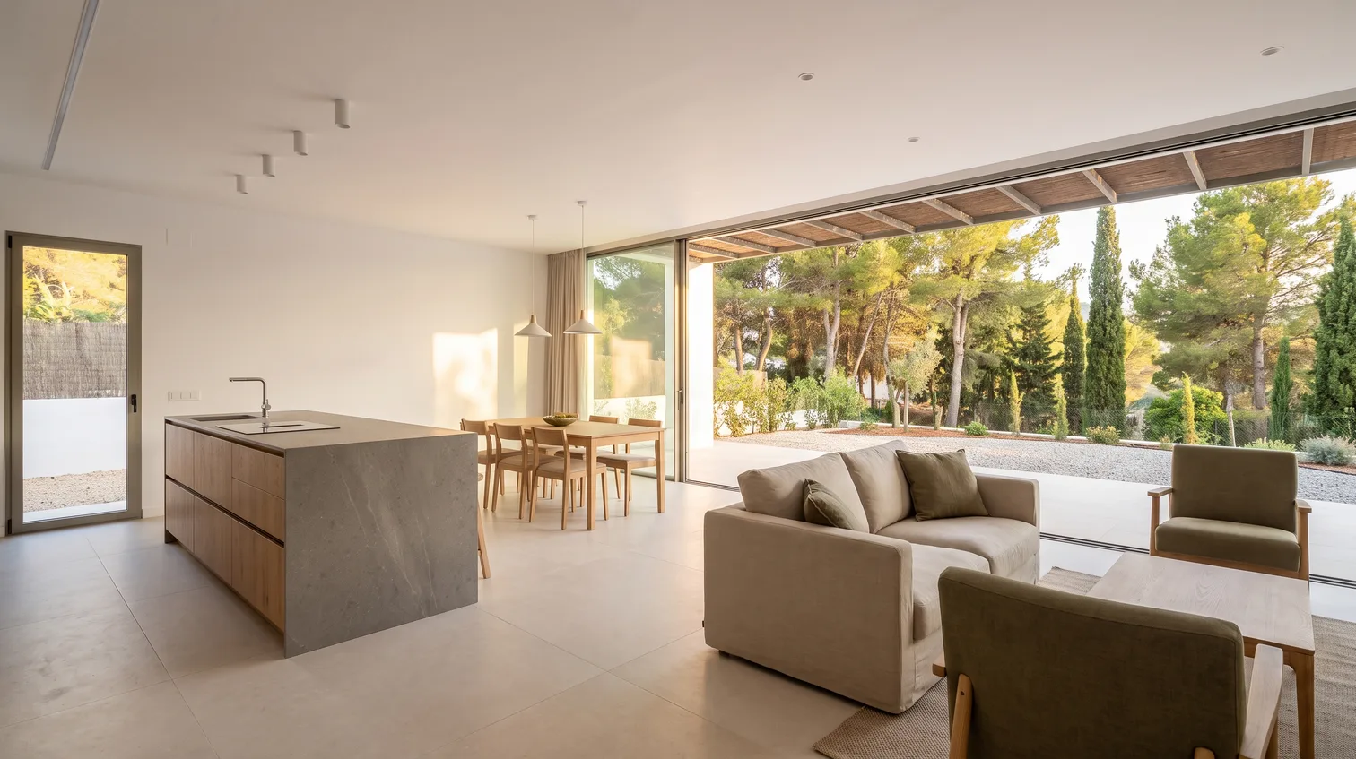 Zona de día de un chalet reformado en El Brillante, Córdoba, con isla de cocina en roble y piedra y un ventanal corredero abierto al jardín